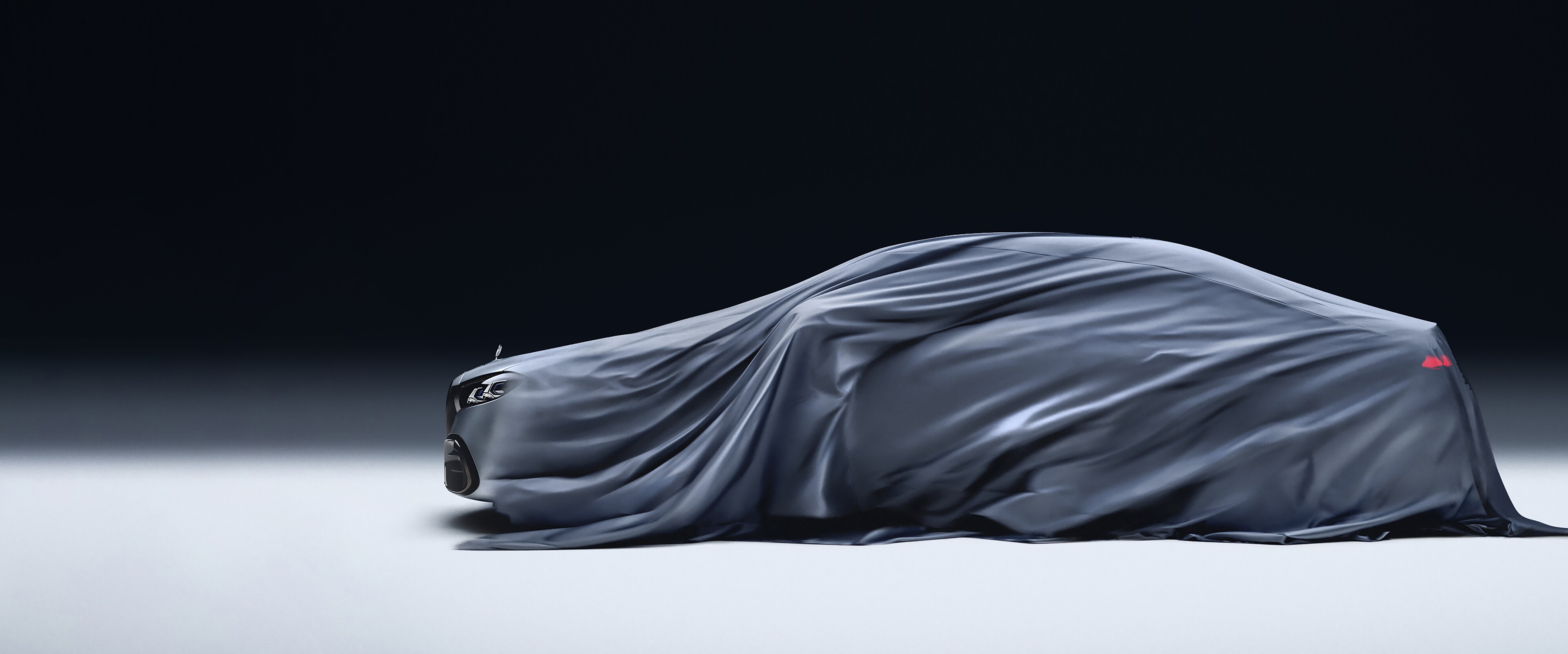 The image shows a car being covered with a dark, silky cloth against a plain dark background