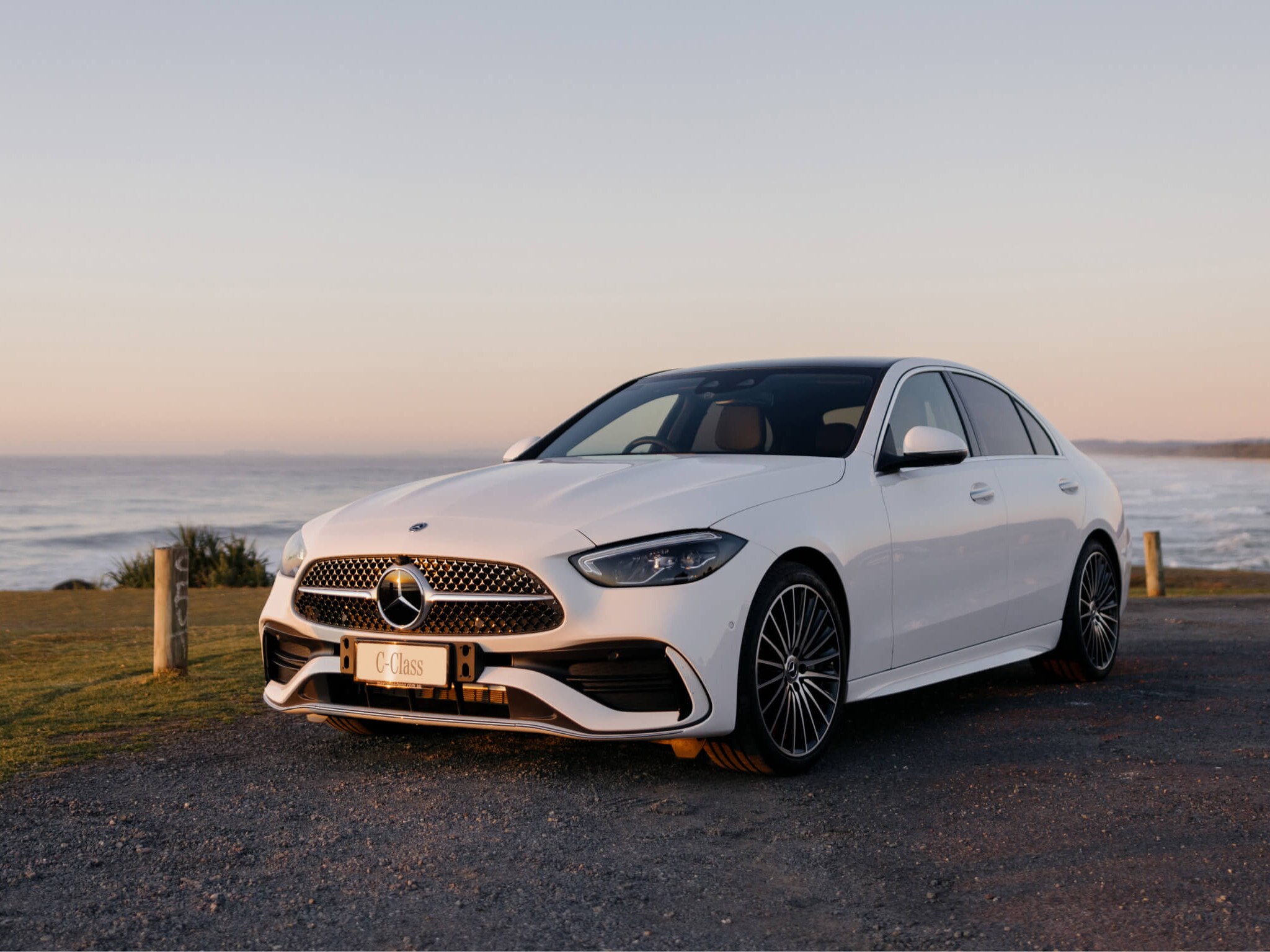 White Mercedes-Benz C 300 parked along the beach coast. 