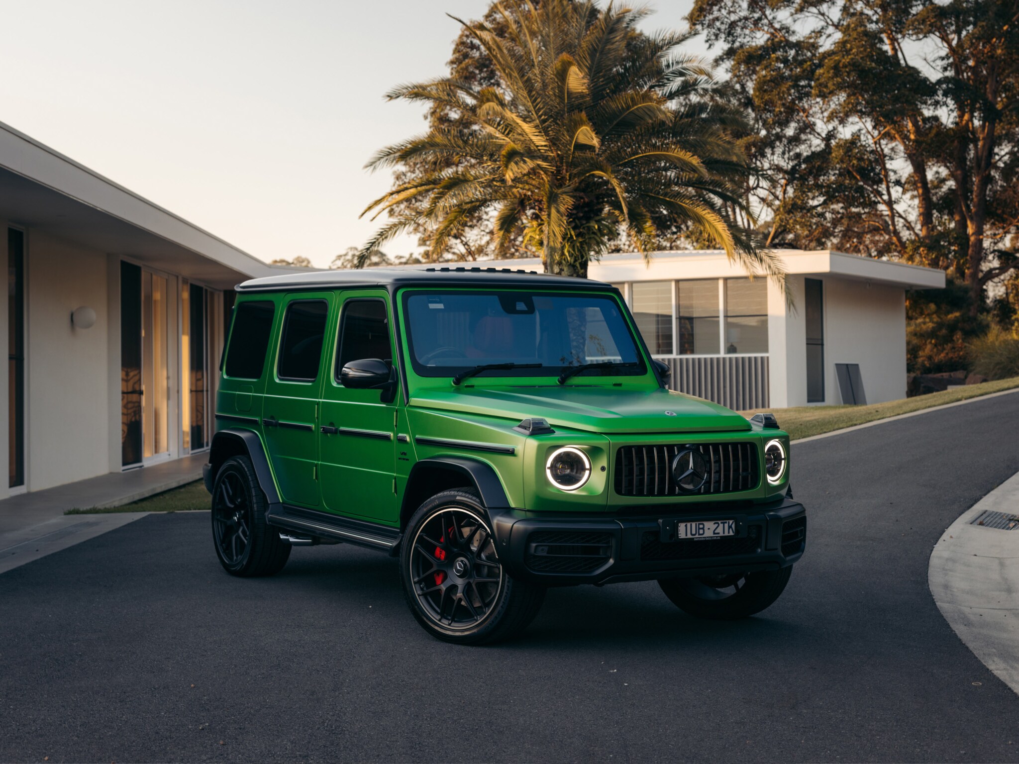 A green Mercedes-AMG G 63 parked in a driveway.