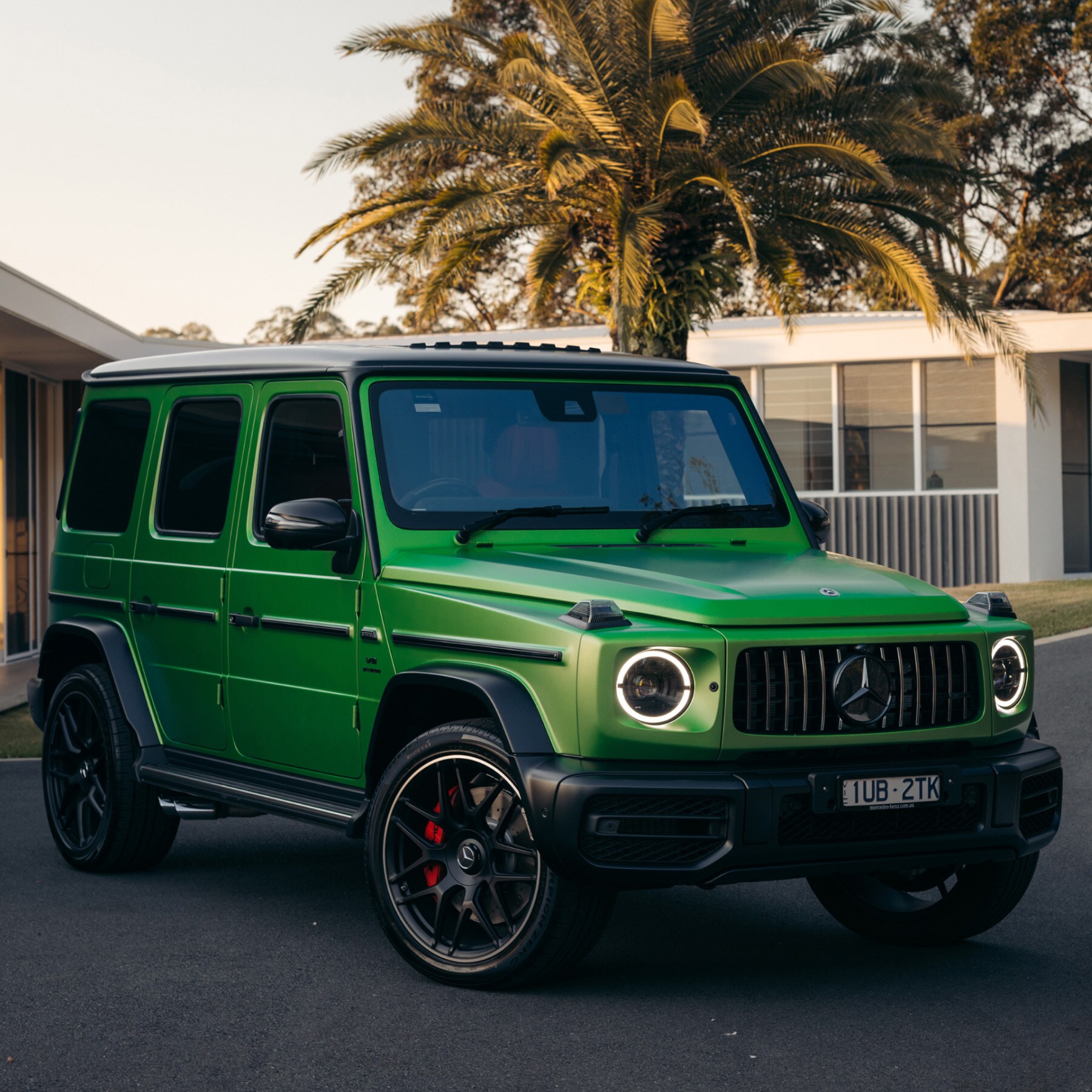 A green Mercedes-AMG G 63 parked in a driveway.
