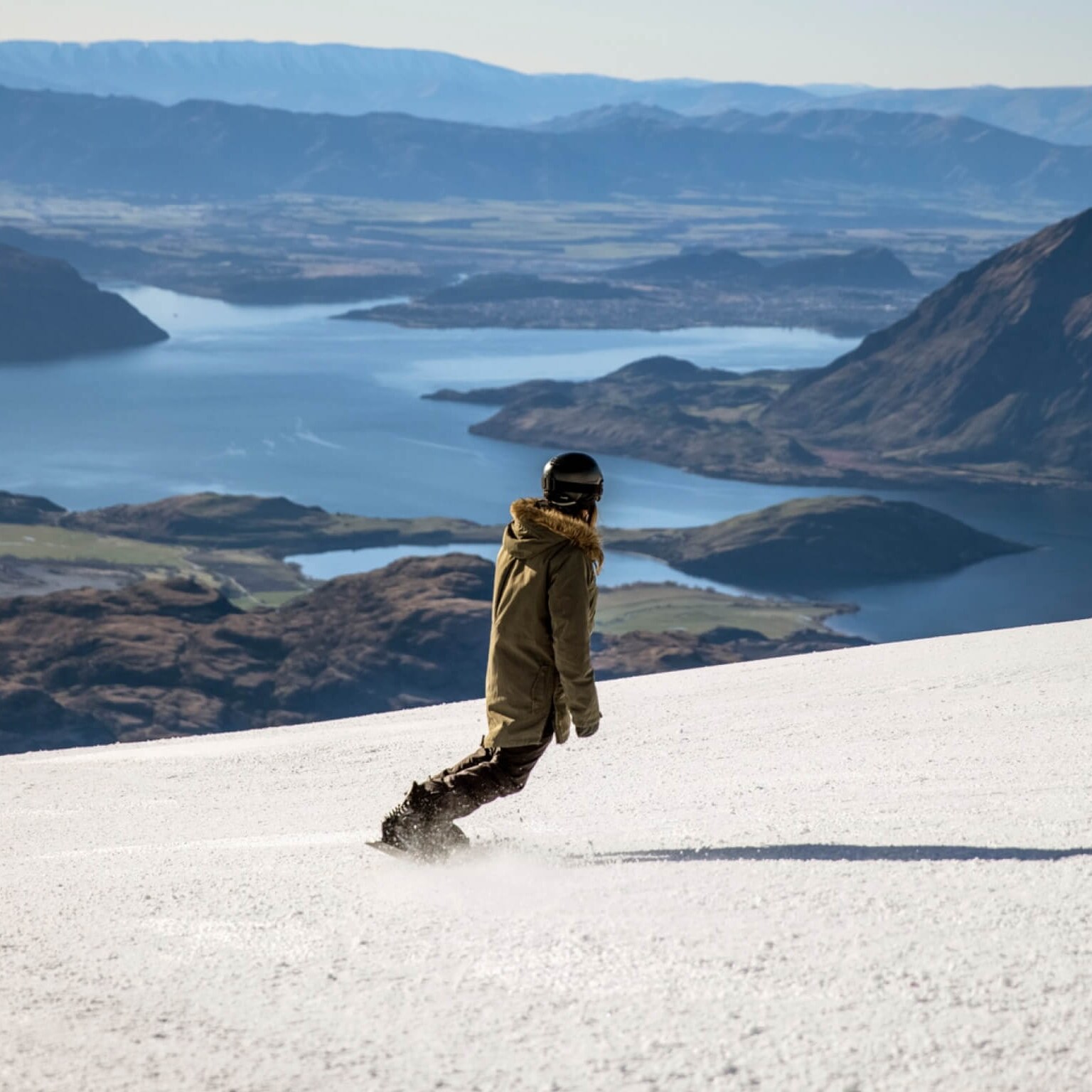 A solo snowboarder at Treble Cone resort with mountain views