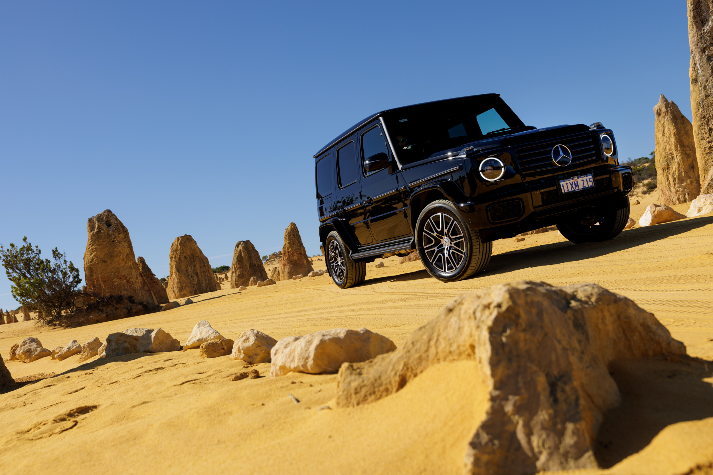 A black Mercedes-Benz G-Class driving through the yellow sands of The Pinnacles Desert in WA. A black Mercedes-Benz G-Class driving through the yellow sands of The Pinnacles Desert in WA.