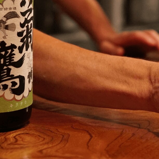 A man passes a glass of sake to a patron
