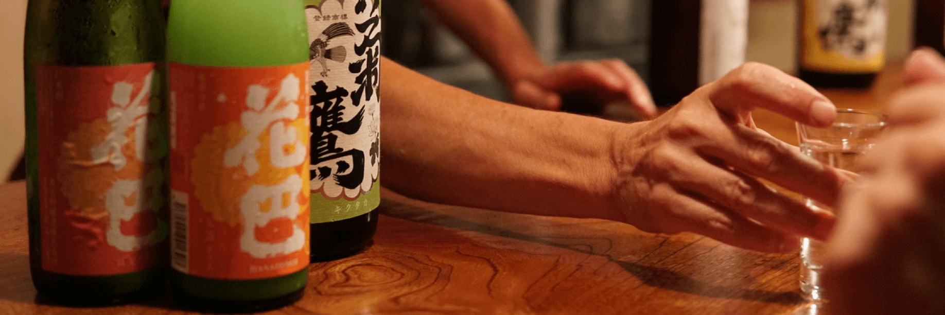 Yoram Ofer at Sake Bar Yoramu A man passes a glass of sake to a patron