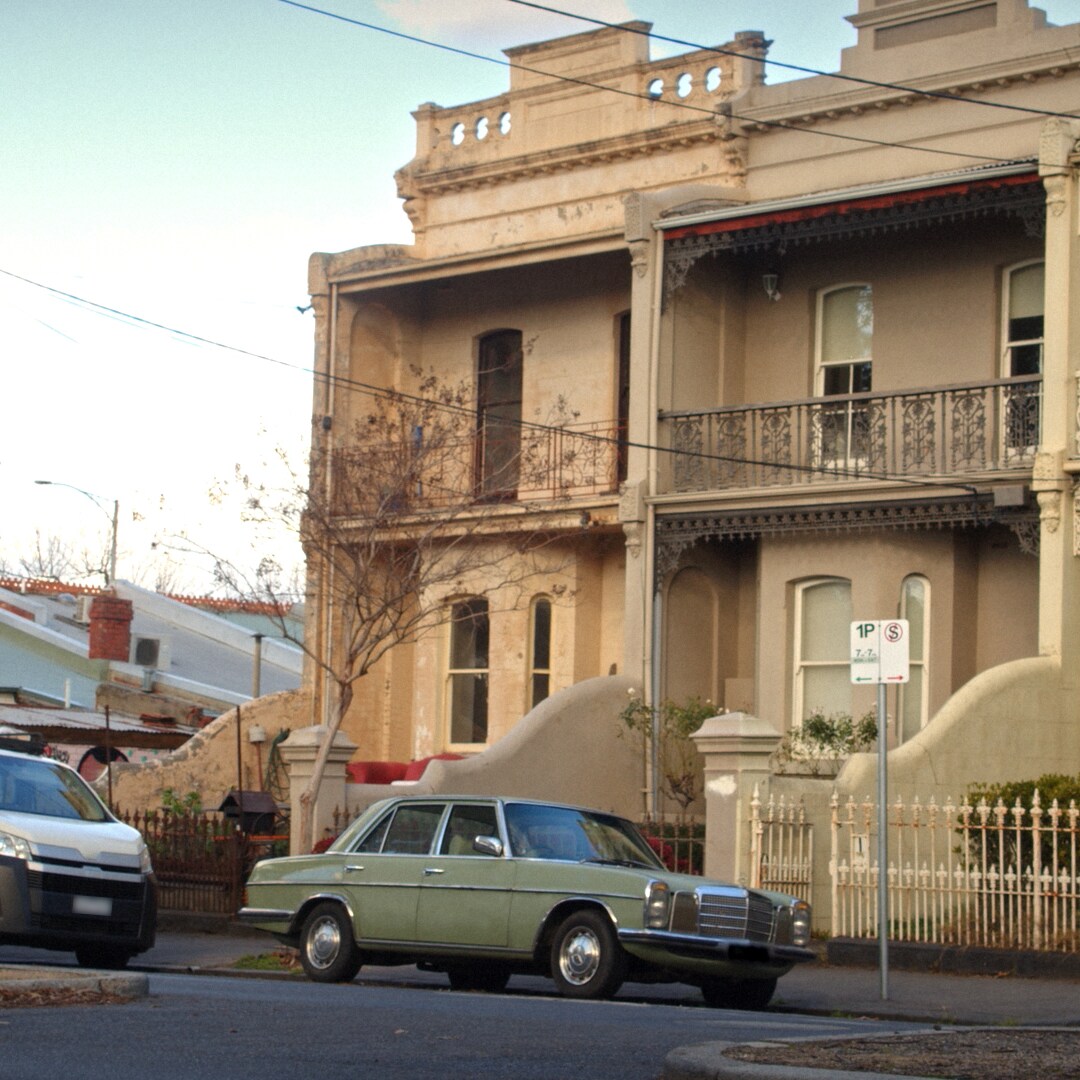 A vintage Mercedes-Benz parked outside a townhouse