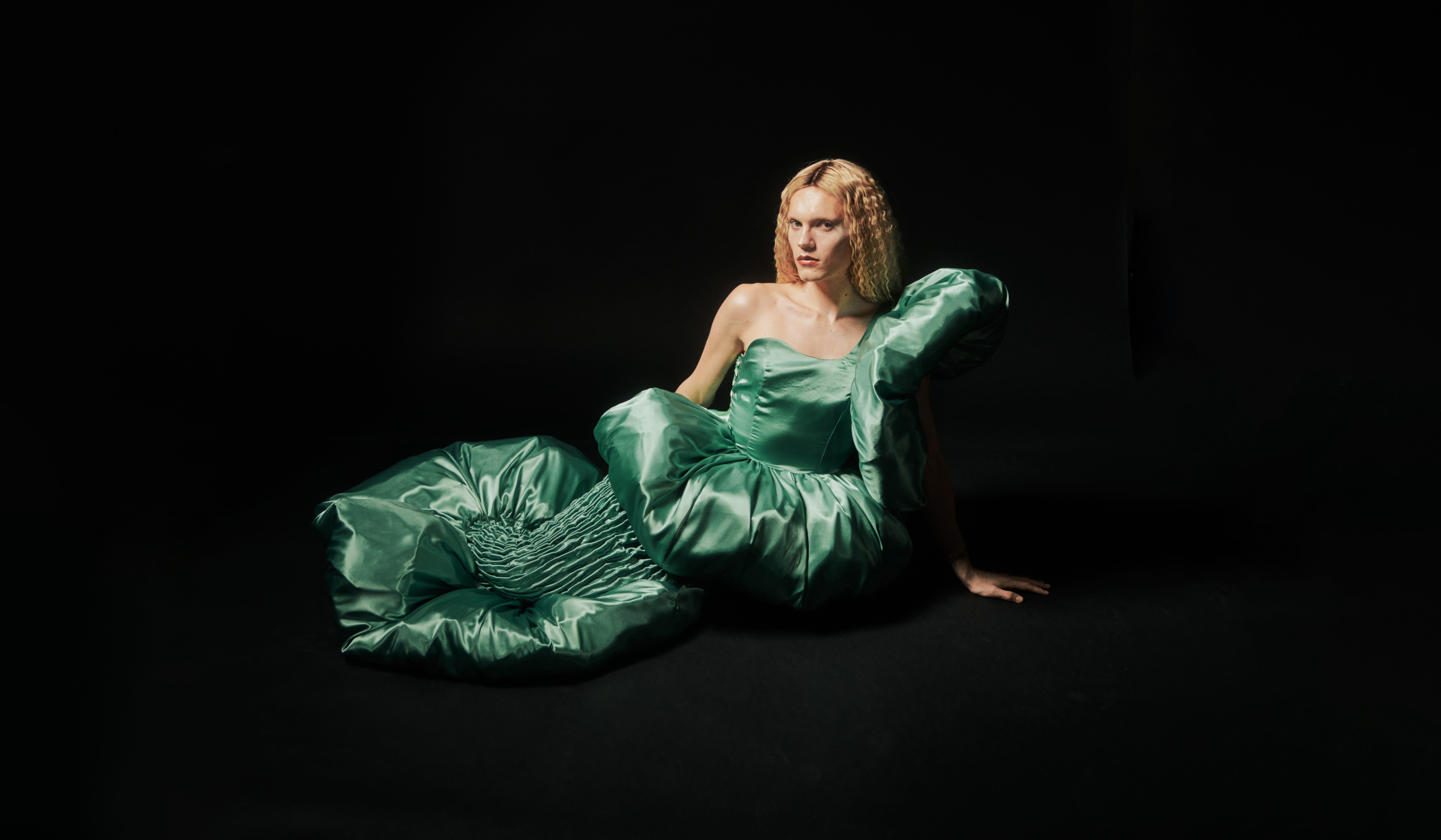 A person in a green dress designed by Jarrod Reid lying on their side. Image credit/photographer: Jess Brohier A person in a green dress designed by Jarrod Reid lying on their side. Image credit/photographer: Jess Brohier