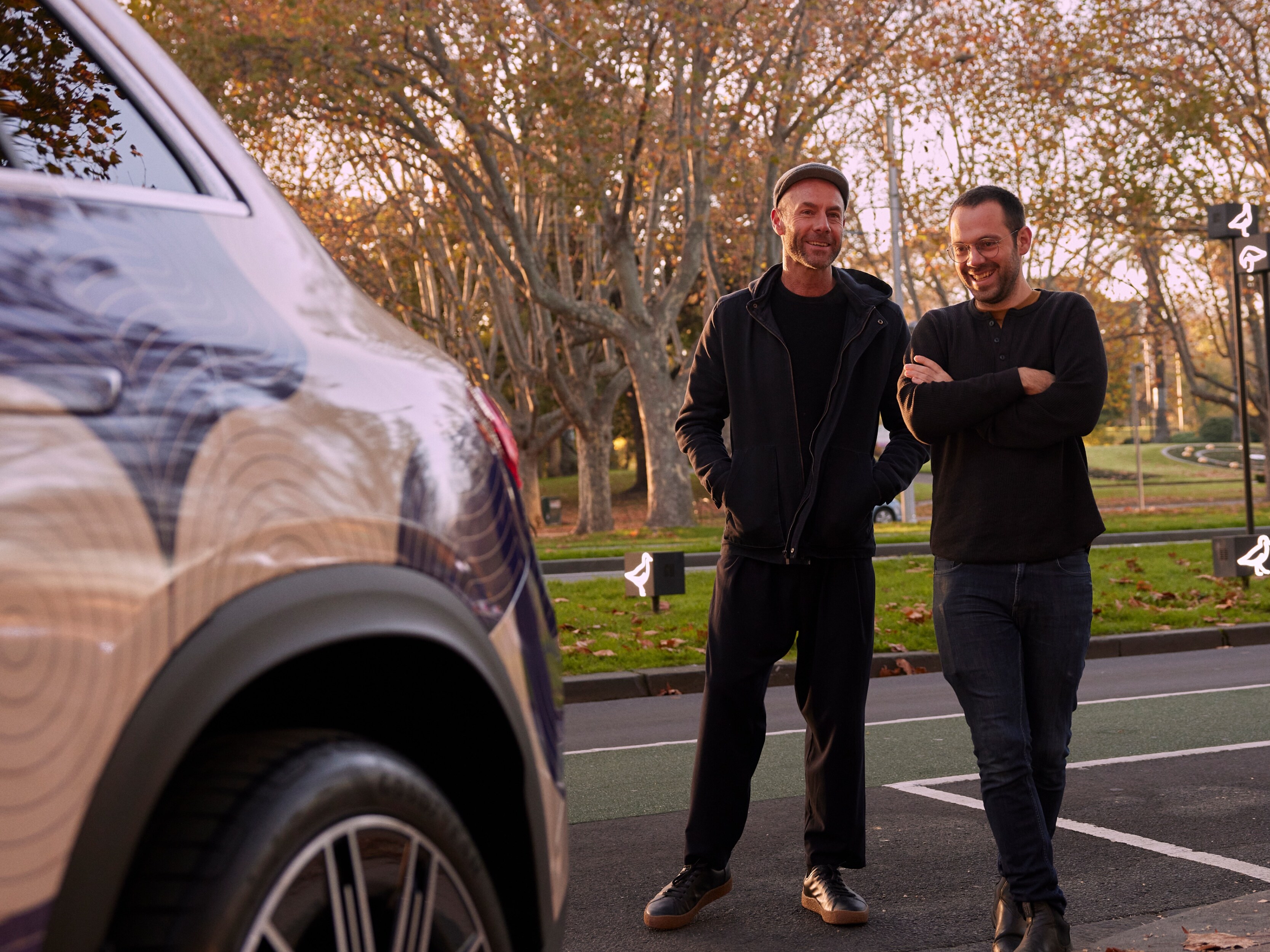 Adam Goodrum and Arthur Seigneur smiling next to a Mercedes-Benz EQE SUV. 
