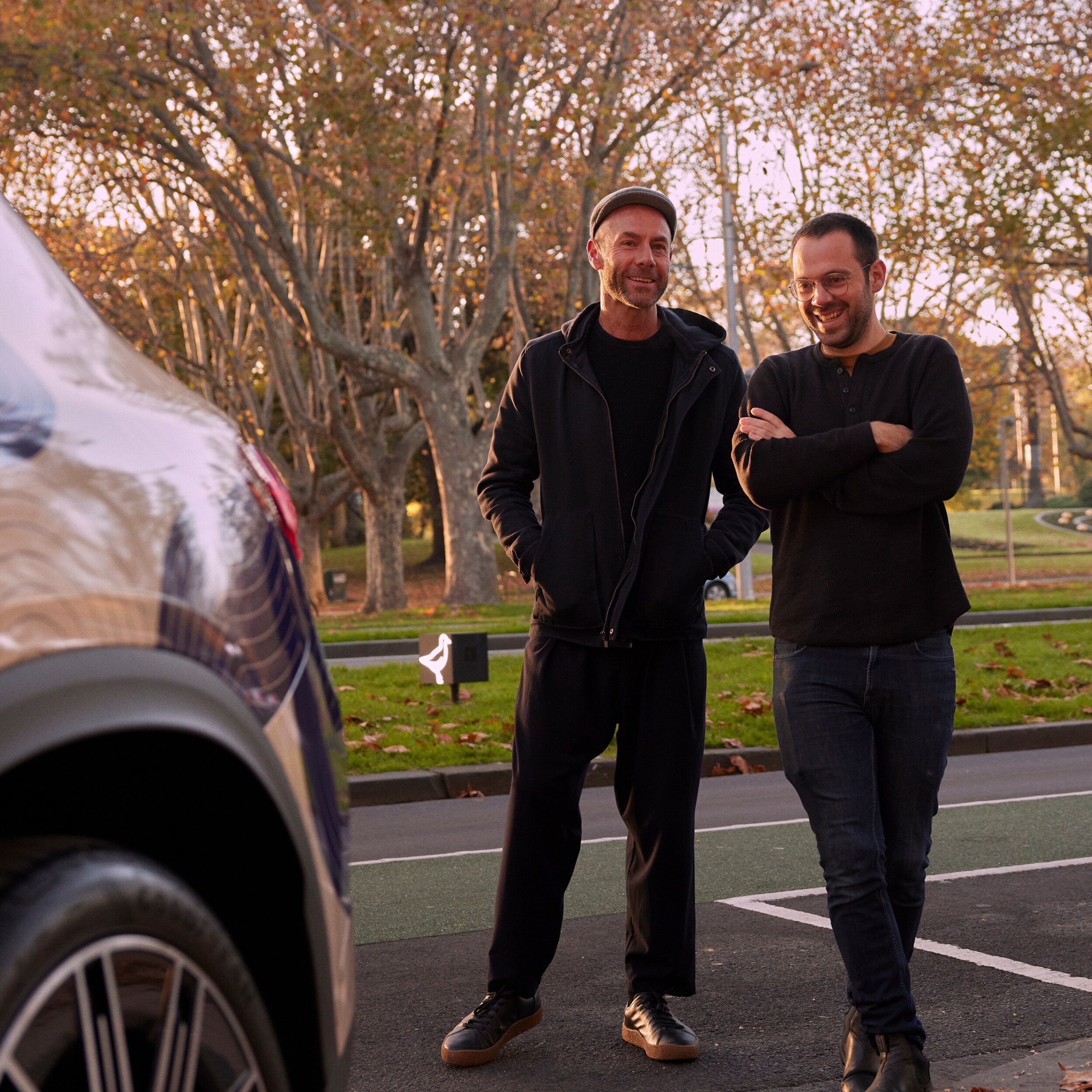 Adam Goodrum and Arthur Seigneur smiling next to a Mercedes-Benz EQE SUV. Image credit/photographer: Sean Fennessy & Lillie Thompson