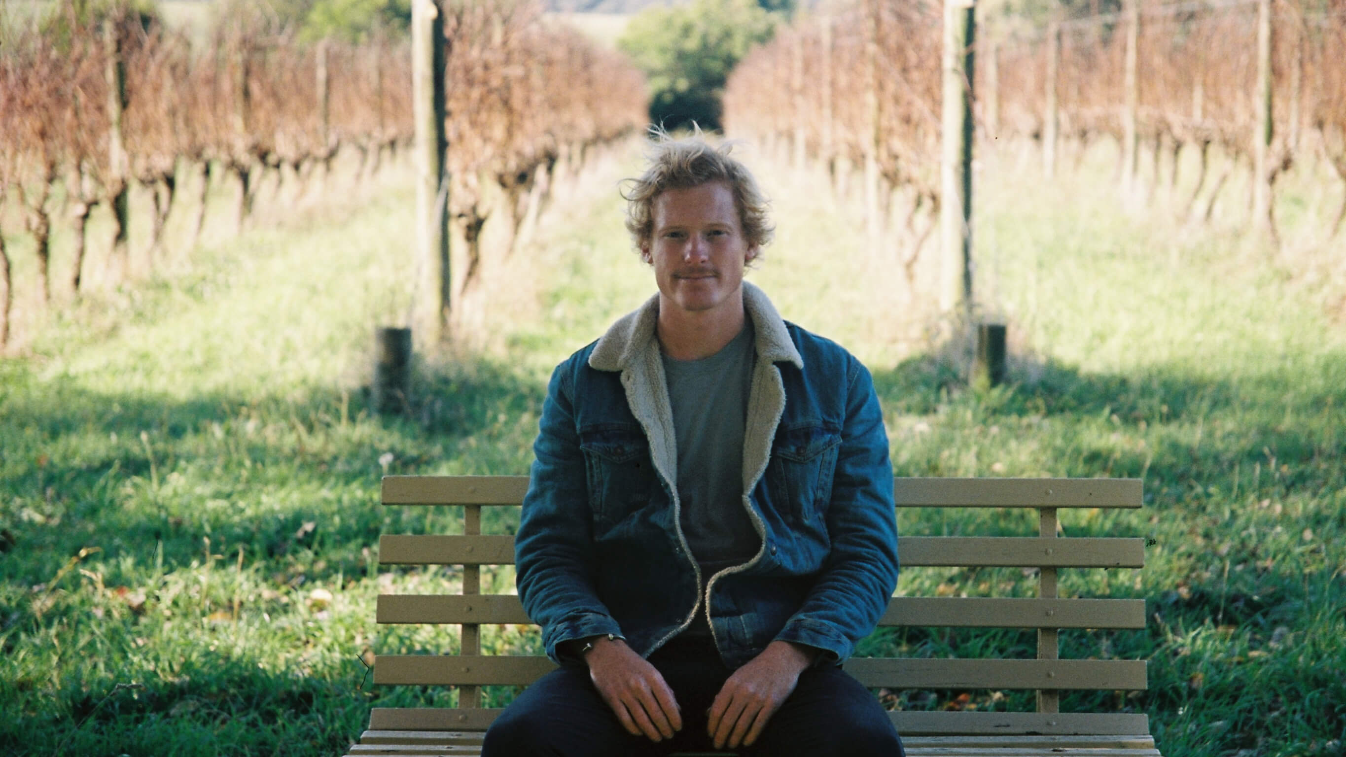 Jordy Kay in front of his vineyard A man sits on a bench in a vineyard