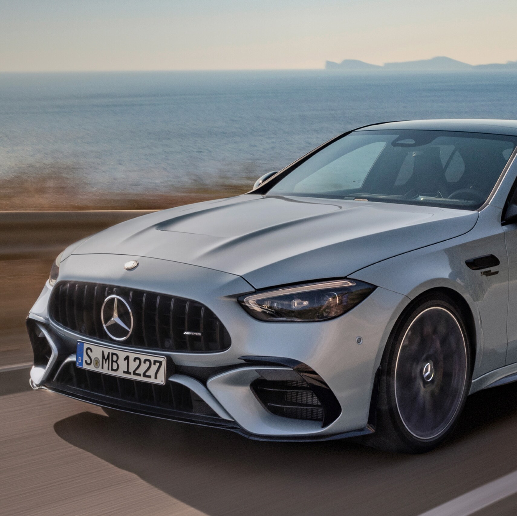 Mercedes-AMG C 63 S E PERFORMANCE Sedan driving along coastal highway.