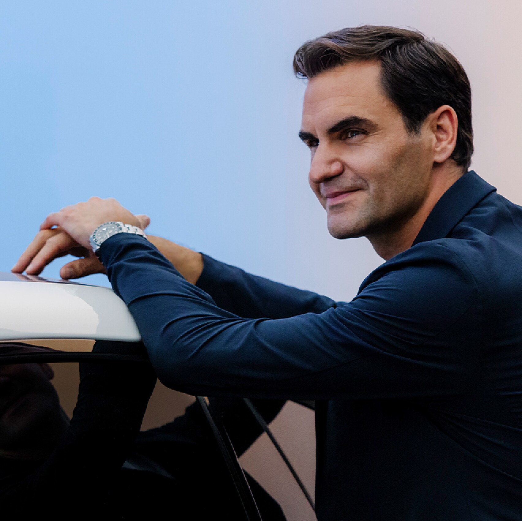 Roger Federer leaning against an all-electric Mercedes-Benz EQS Sedan and smiling.