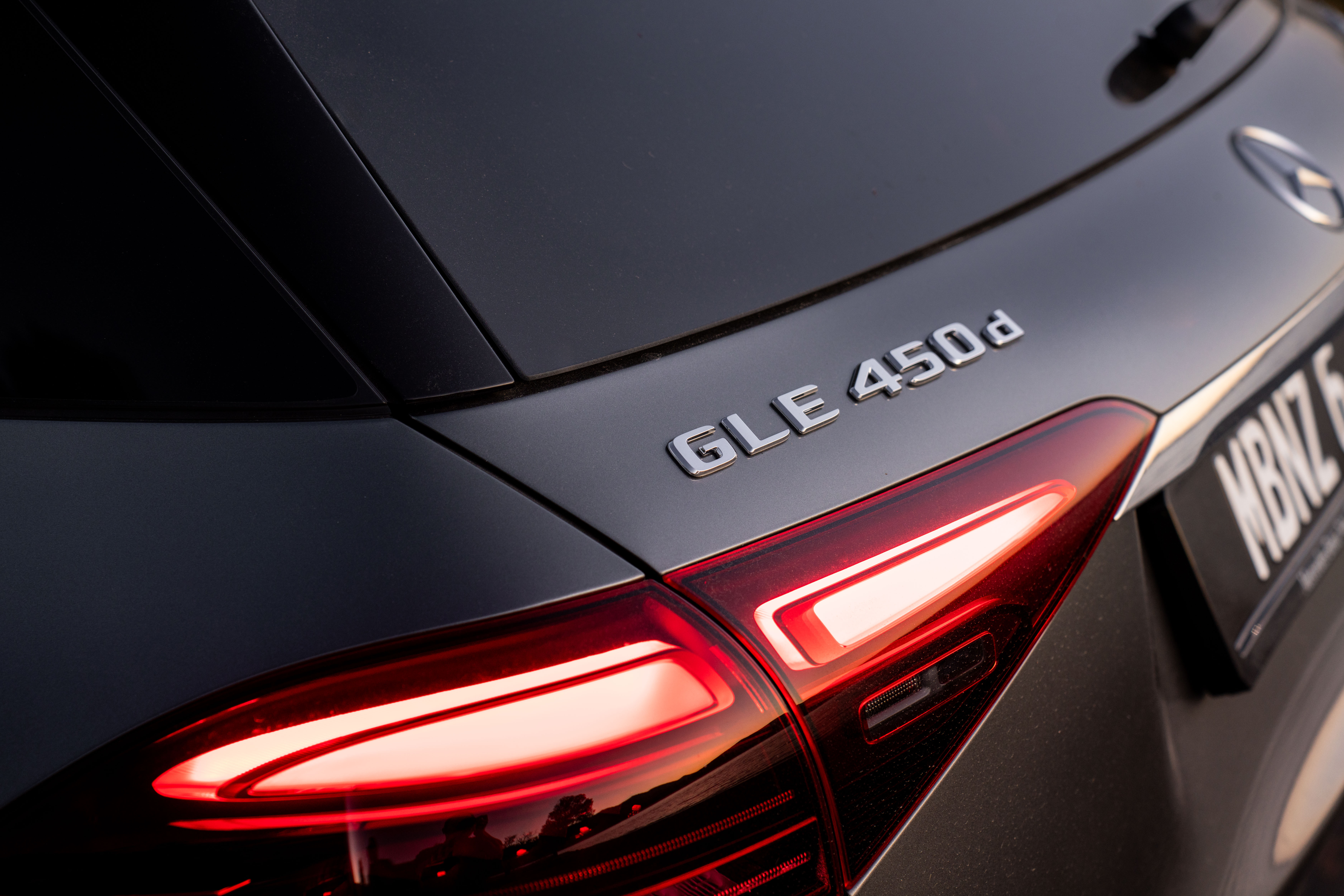 A close-up of the badge of a Mercedes-Benz GLE 450 d. A close-up of the badge of a Mercedes-Benz GLE 450 d.
