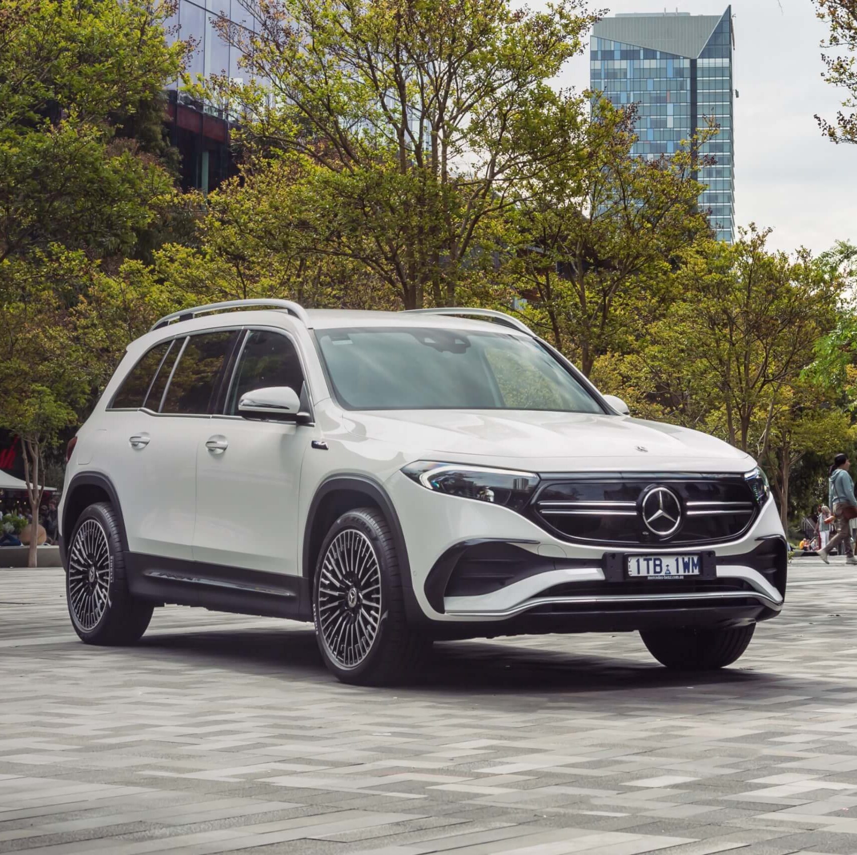 White EQB 250 SUV parked in front of office building with green trees.