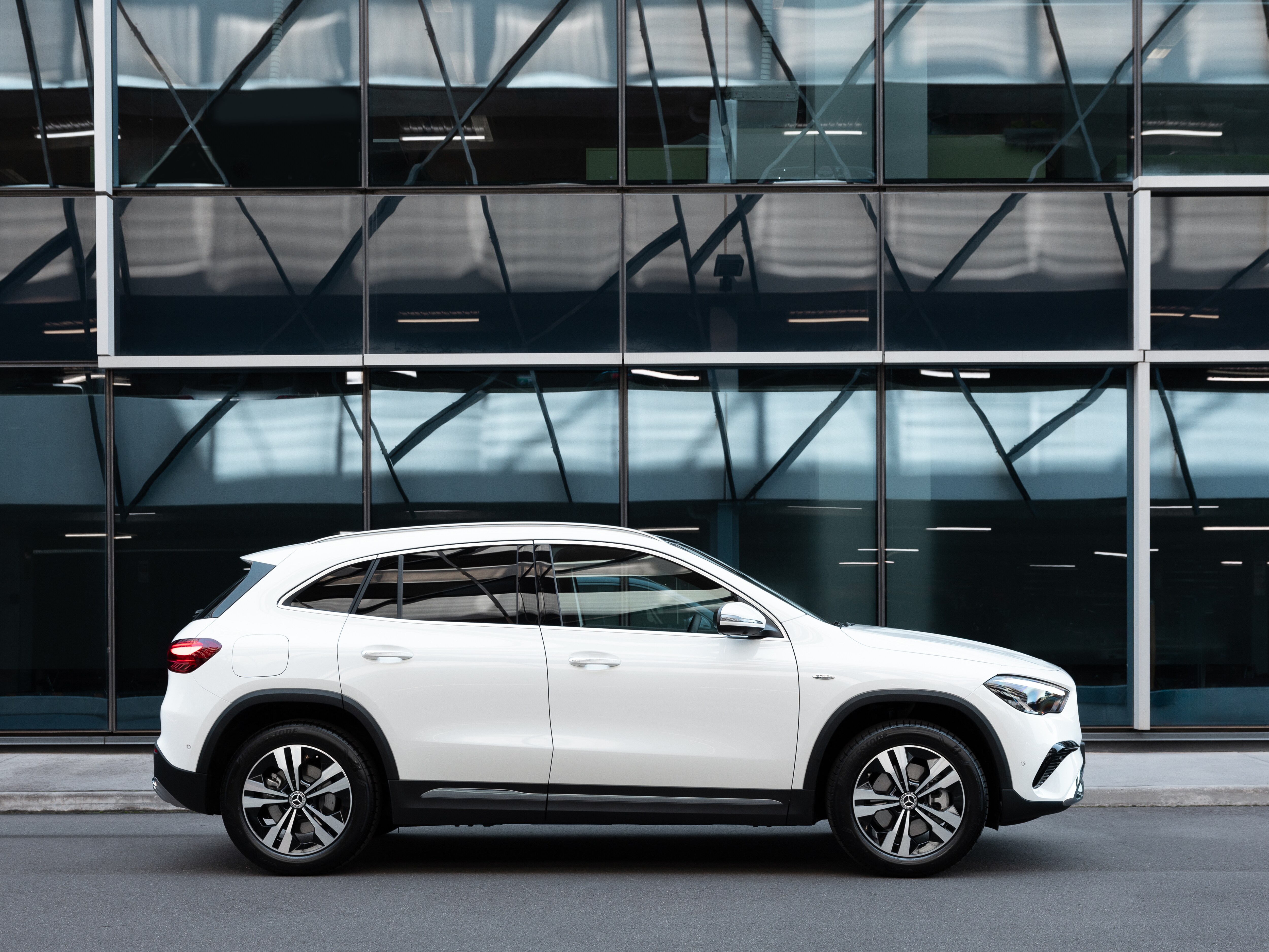 A white Mercedes-Benz GLA 250 e parked in front of a building