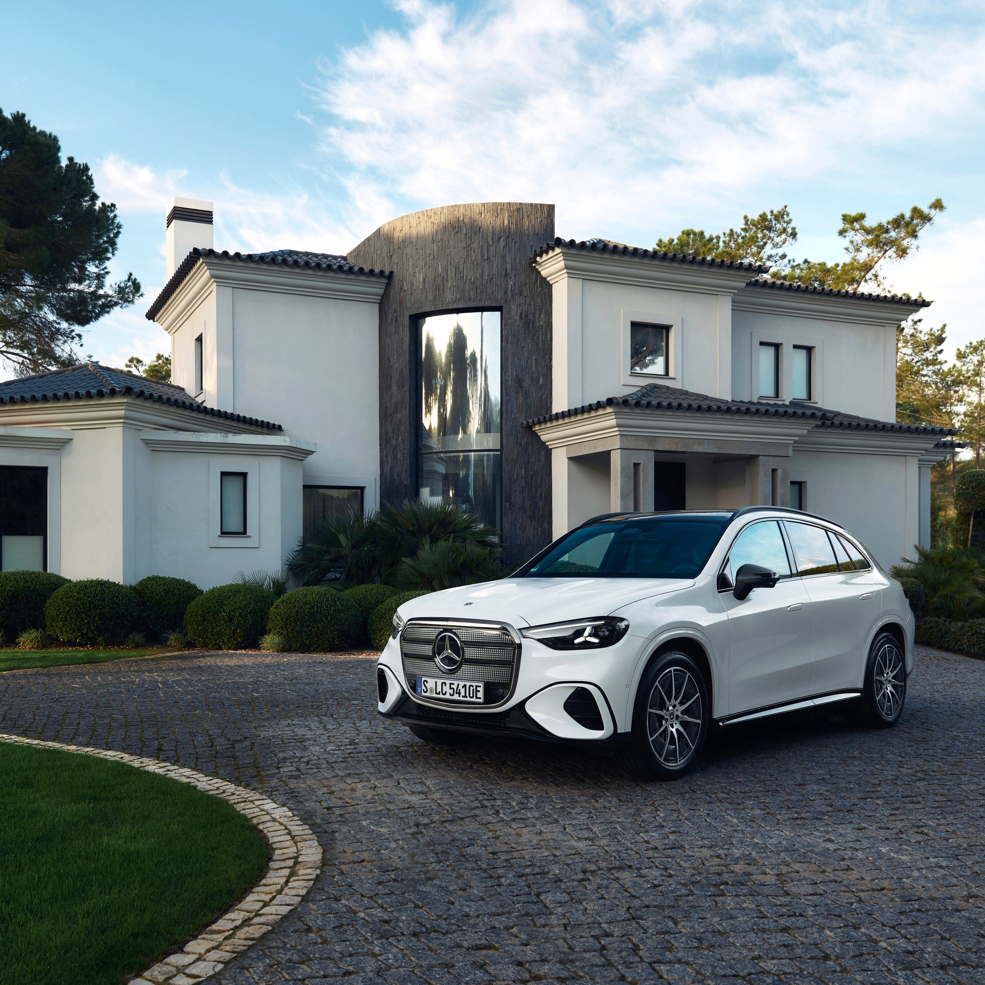 A white SUV parked in the driveway of a house.Image credit/photographer: Mercedes-Benz Group AG