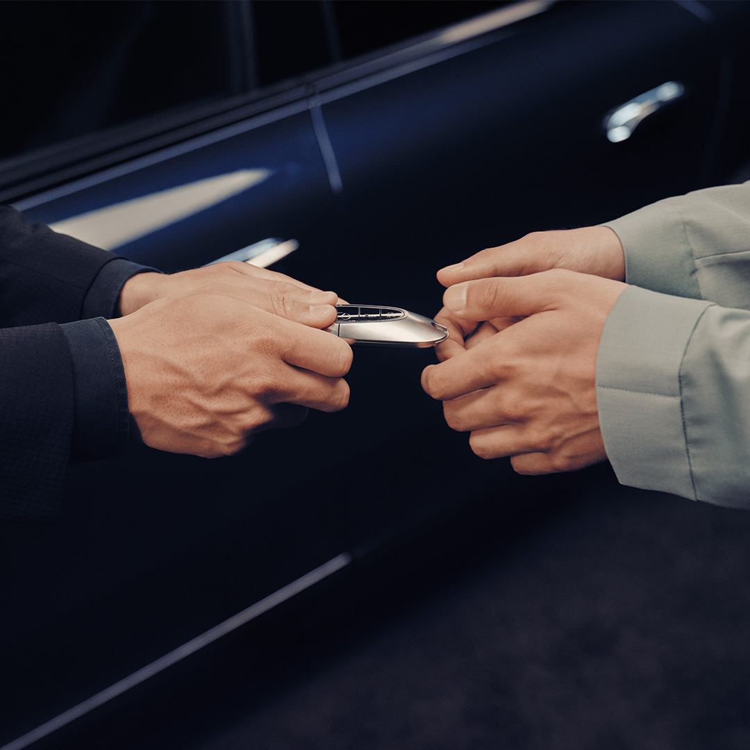Financing with Mercedes-Benz. A Business Manager handing over a new set of Mercedes-Benz keys to a customer.