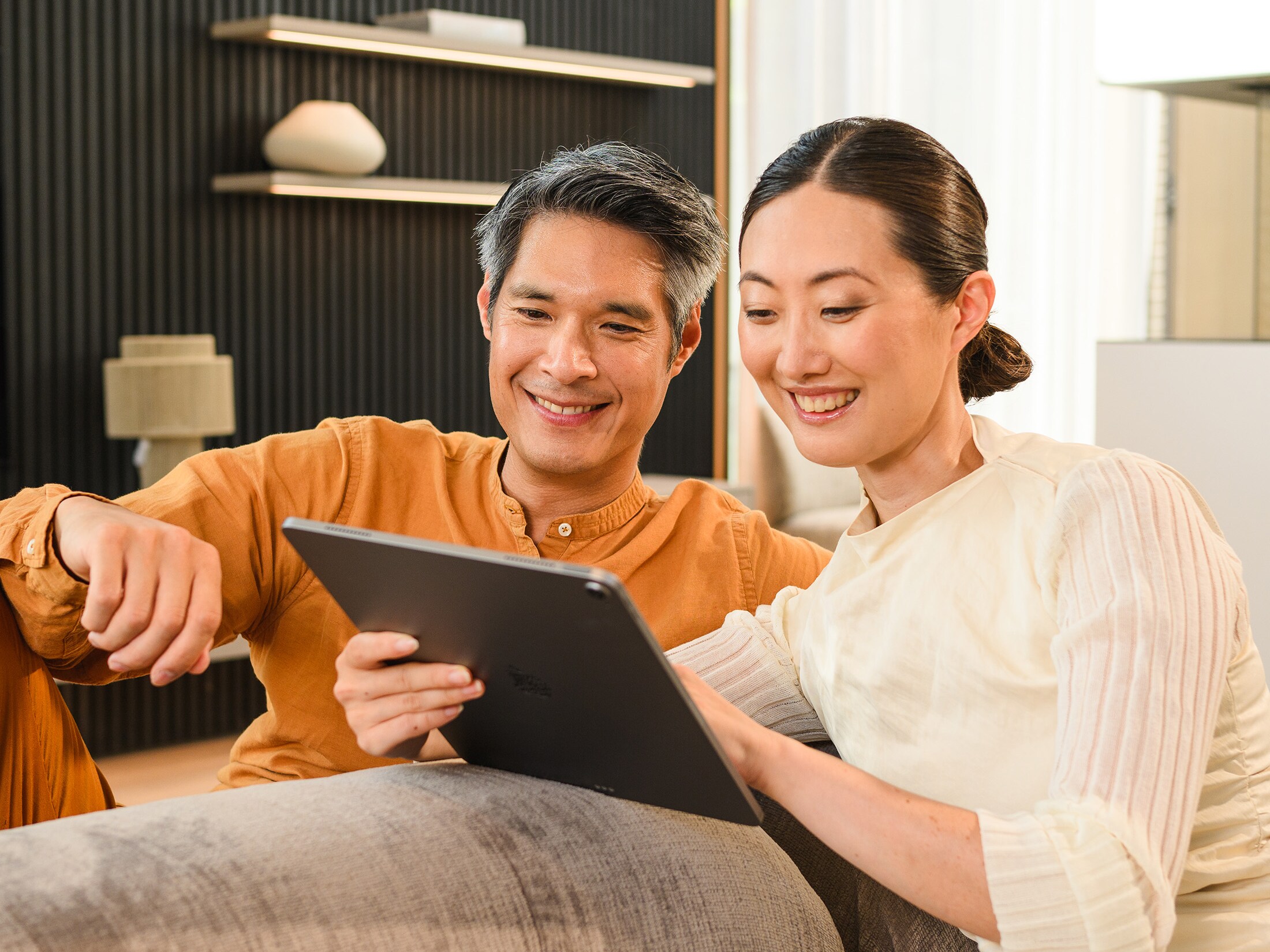 Two people on a sofa looking at a mobile device.