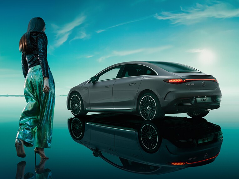 The all-electric EQE from Mercedes-Benz standing in its green EQ world with a mirroring floor surface.