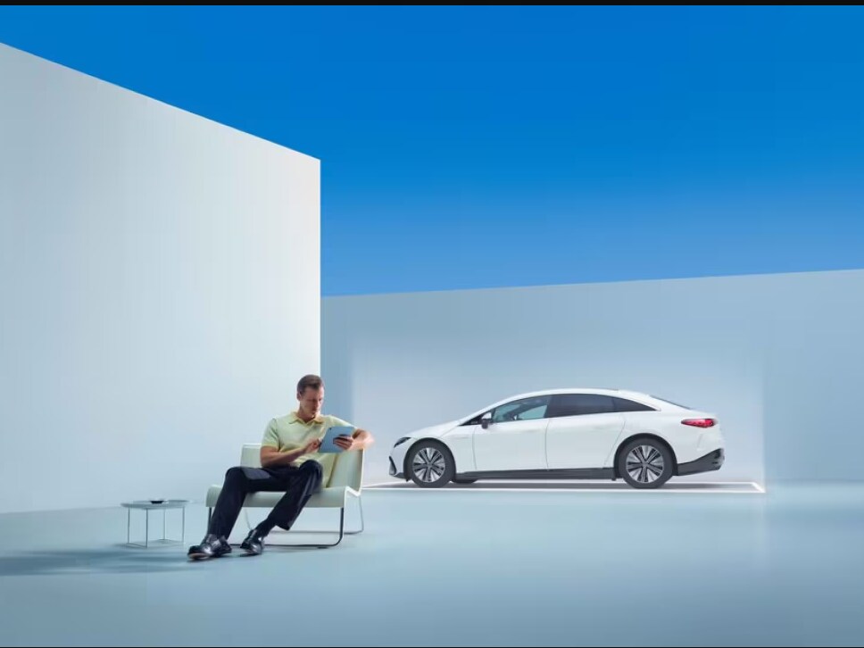 A man checking his tablet in front of a Mercedes-Benz.