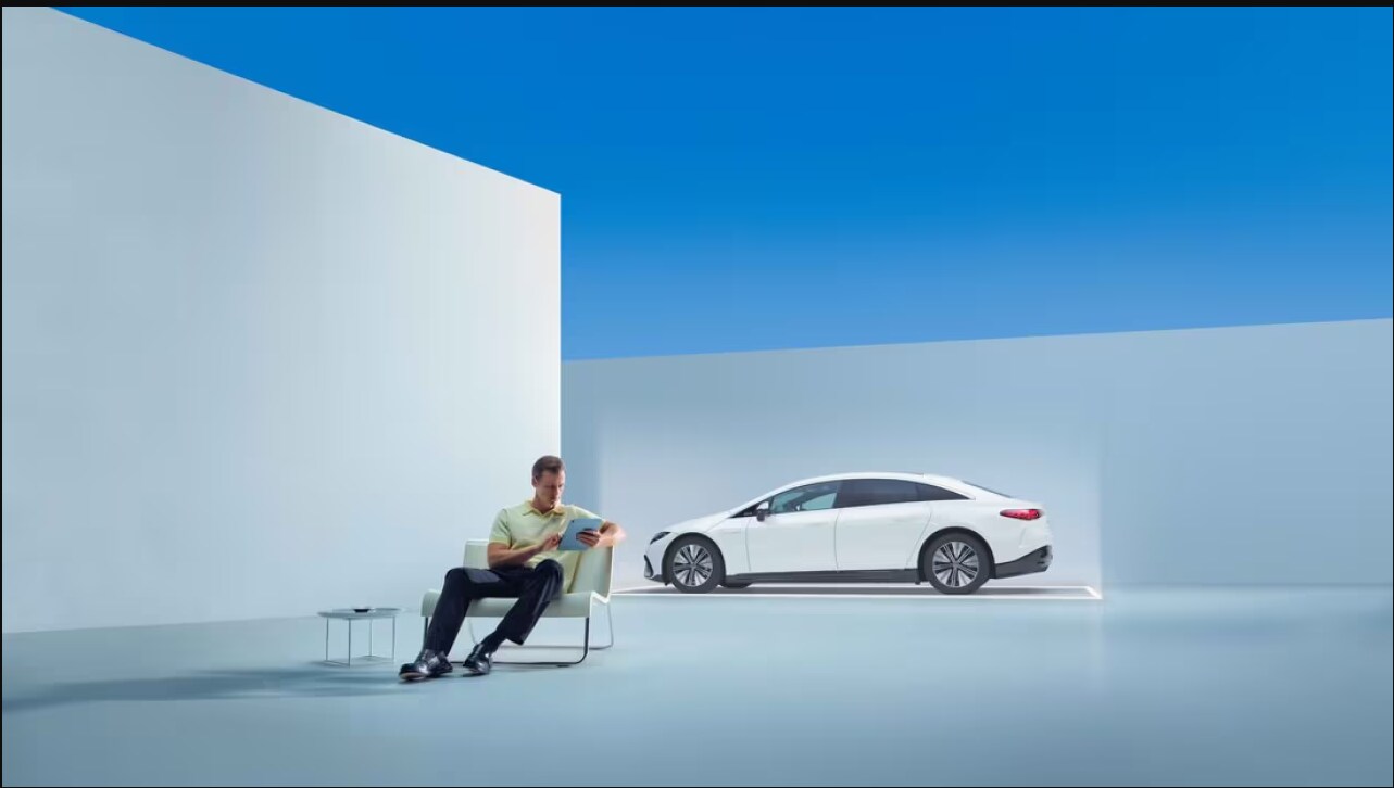 A man checking his tablet in front of a Mercedes-Benz.