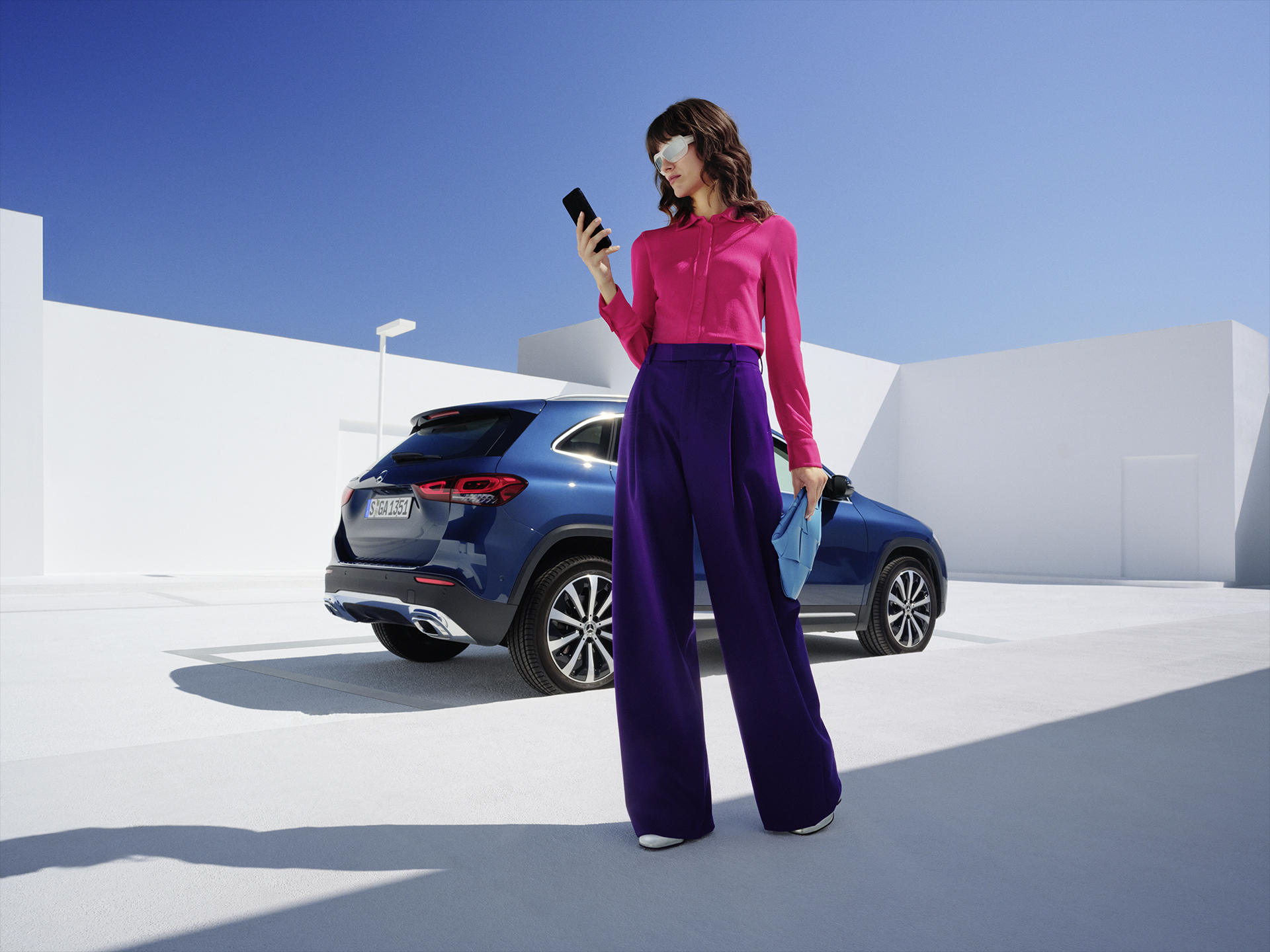 Mercedes me ID | Digital Extras | Mercedes-Benz Women stands in front of the Mercedes-Benz GLA and is looking on her phone.