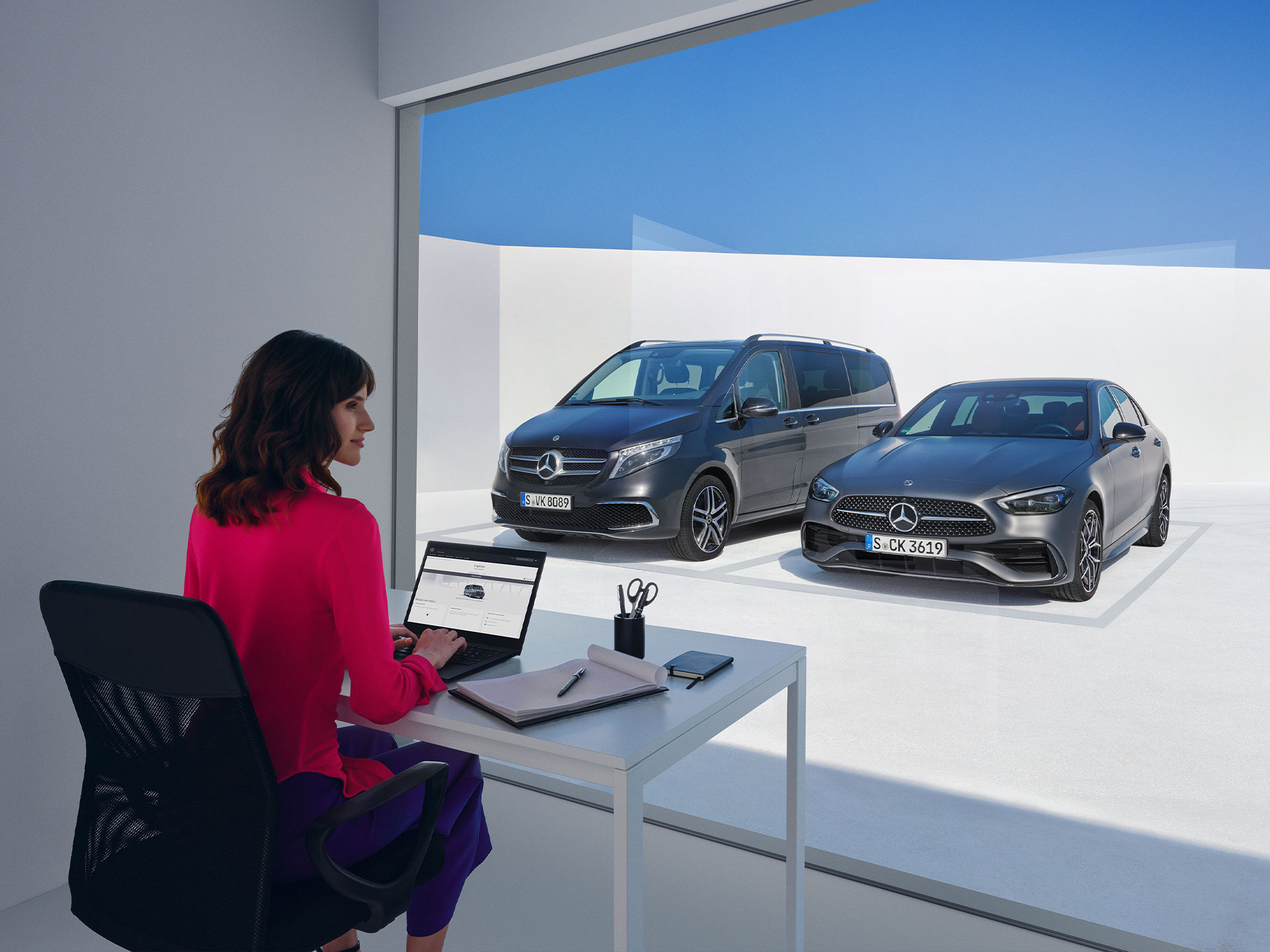 Digital Extras | Mercedes-Benz Women sitting in front of the Mercedes-Benz V-Class and C-Class and looking at a laptop.