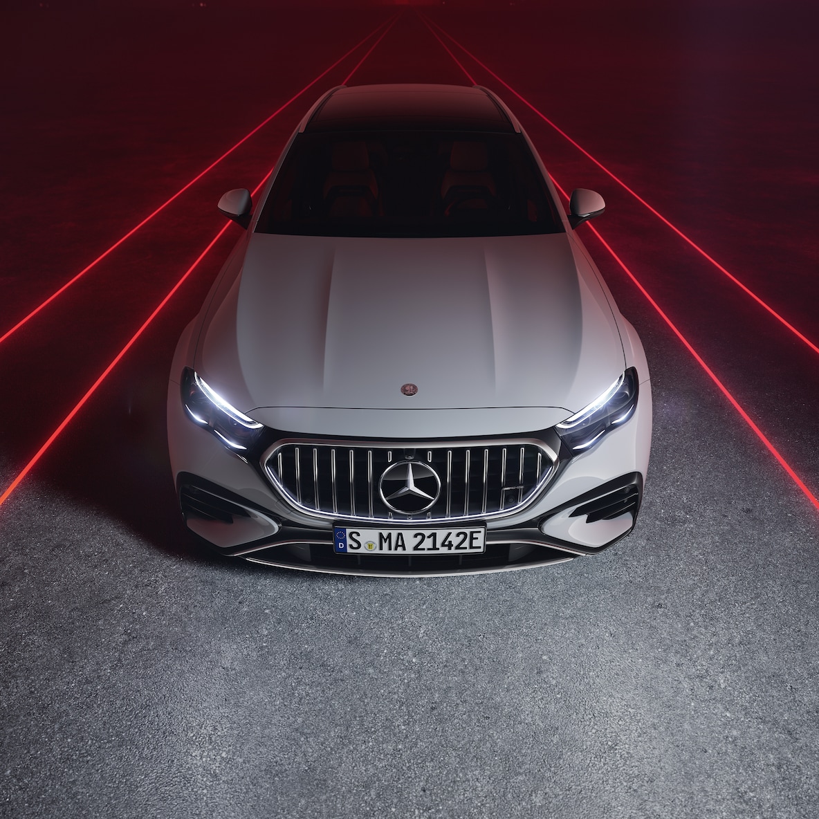 Mercedes-AMG E 53 HYBRID 4MATIC+ in the front view against a red background, seen from above.