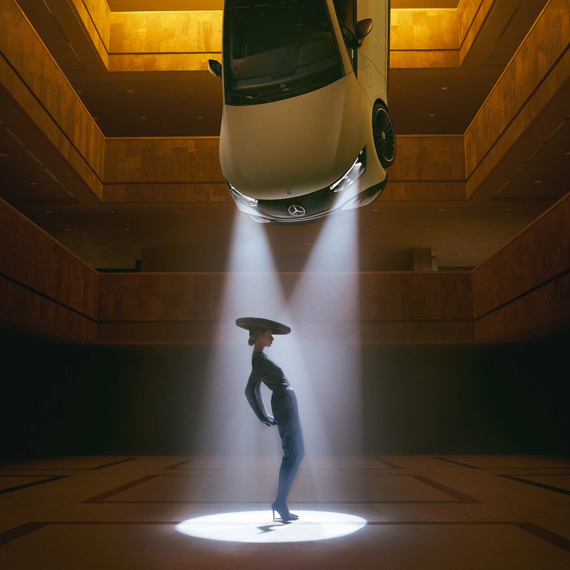 DIGITAL LIGHT lighting technology from Mercedes-Benz A dark room with spotlights hanging from the ceiling and a woman standing in the cone of light.