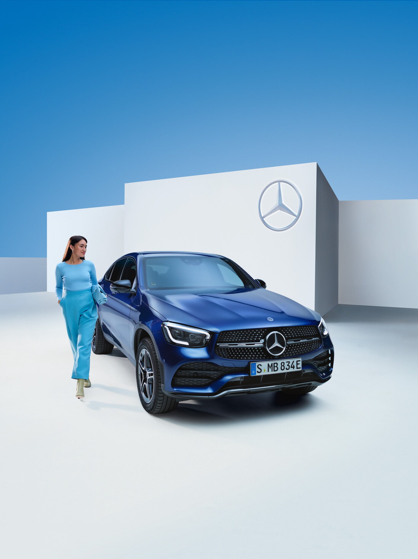 A woman standing next to her Mercedes-Benz.