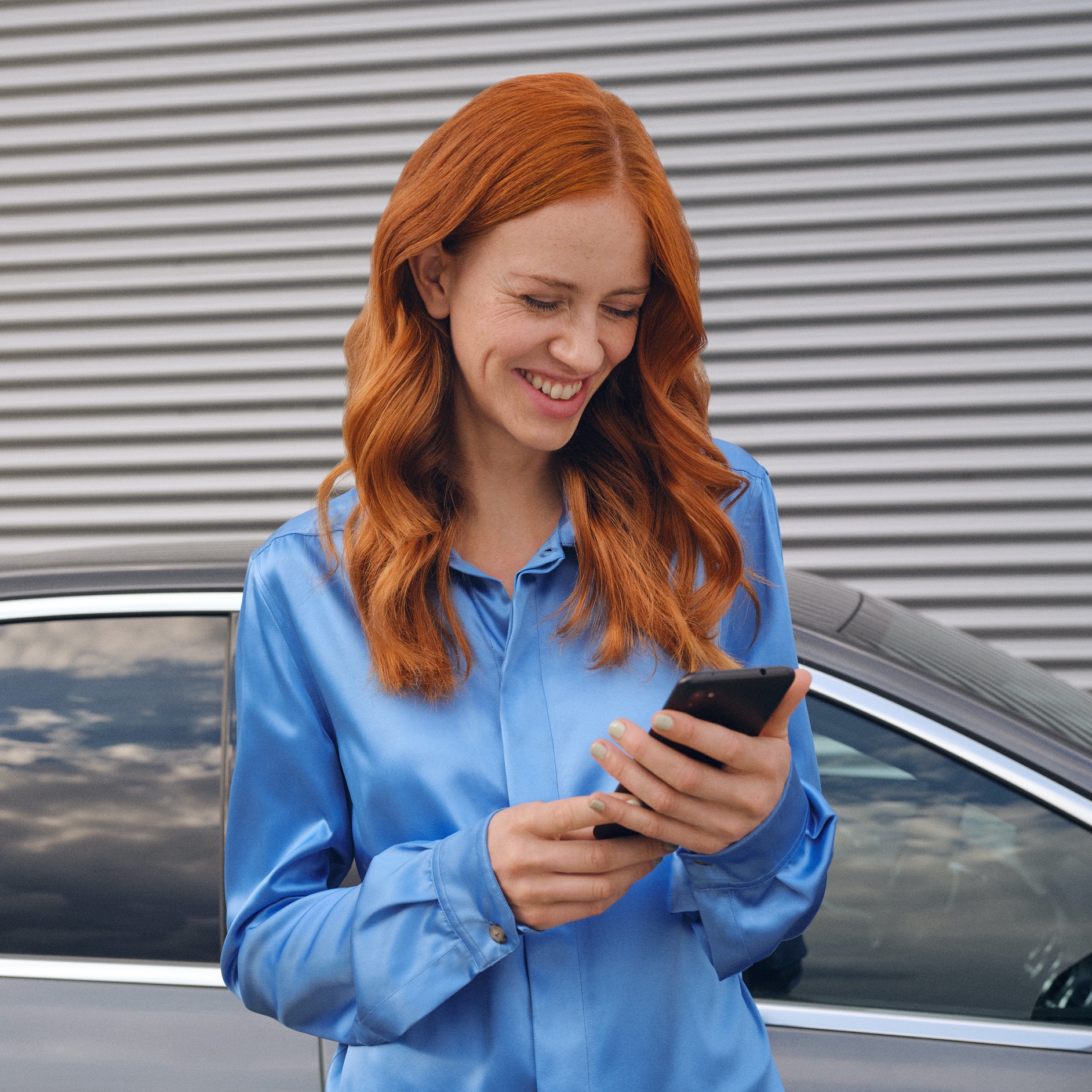 A woman connects to her Mercedes-Benz via the Mercedes me App on her smartphone. A woman connects to her Mercedes-Benz via the Mercedes me App on her smartphone.