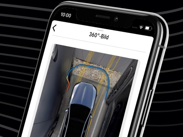 A Mercedes-Benz is conveniently steered into a tight parking space using the Mercedes me Remote Parking App and the 360° view on a smartphone.