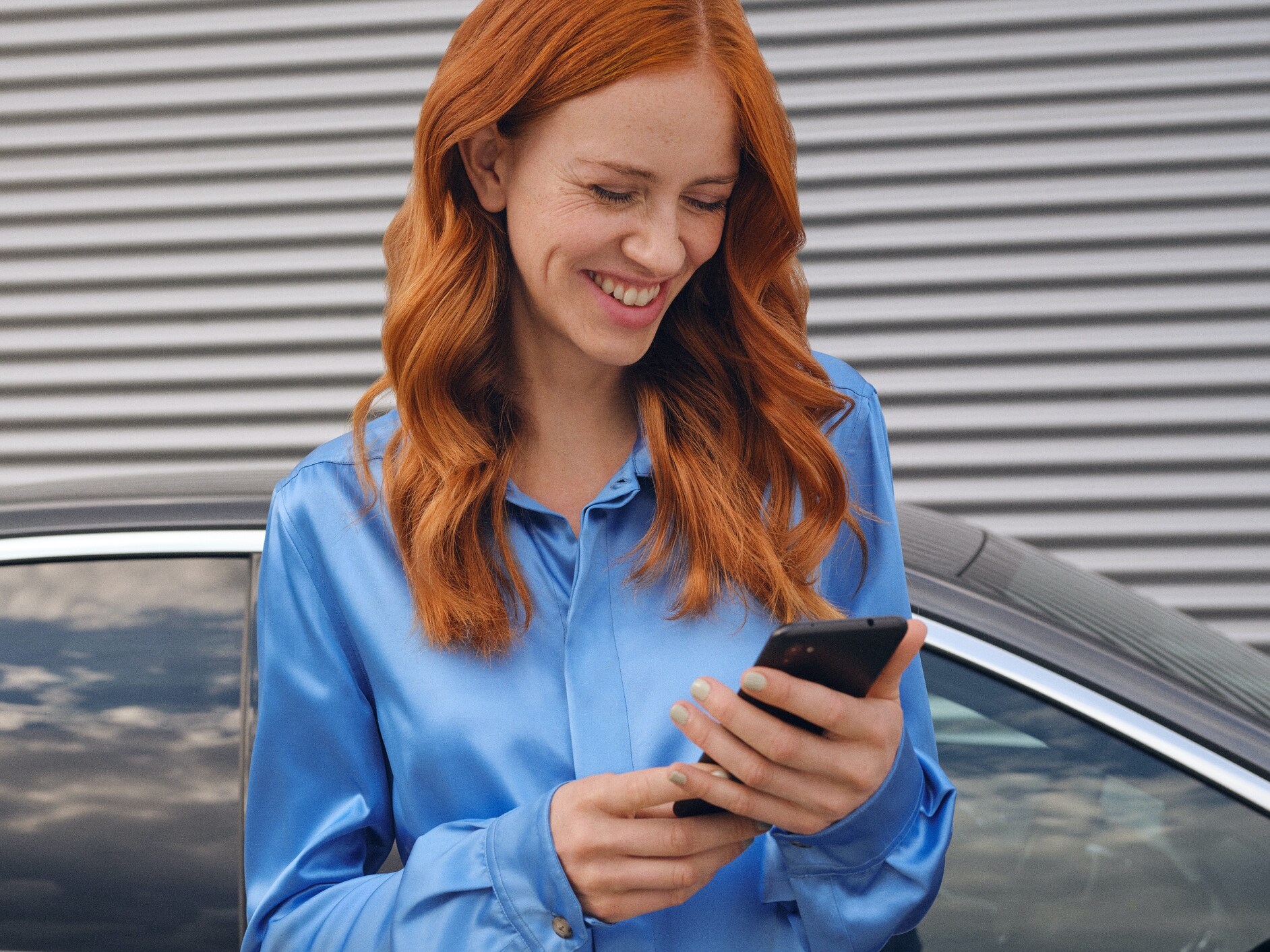 A woman connects to her Mercedes-Benz via the Mercedes-Benz App on her smartphone.