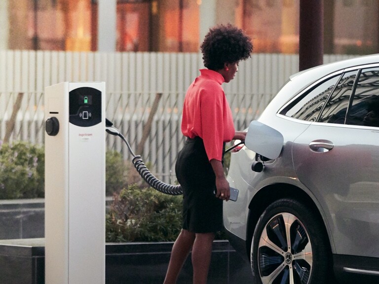 A woman has started the charging process of her Mercedes-Benz via smartphone and Mercedes me Charge.