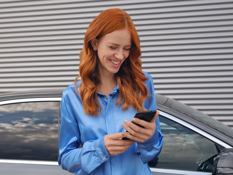 A woman connects to her Mercedes-Benz via the Mercedes me App on her smartphone.