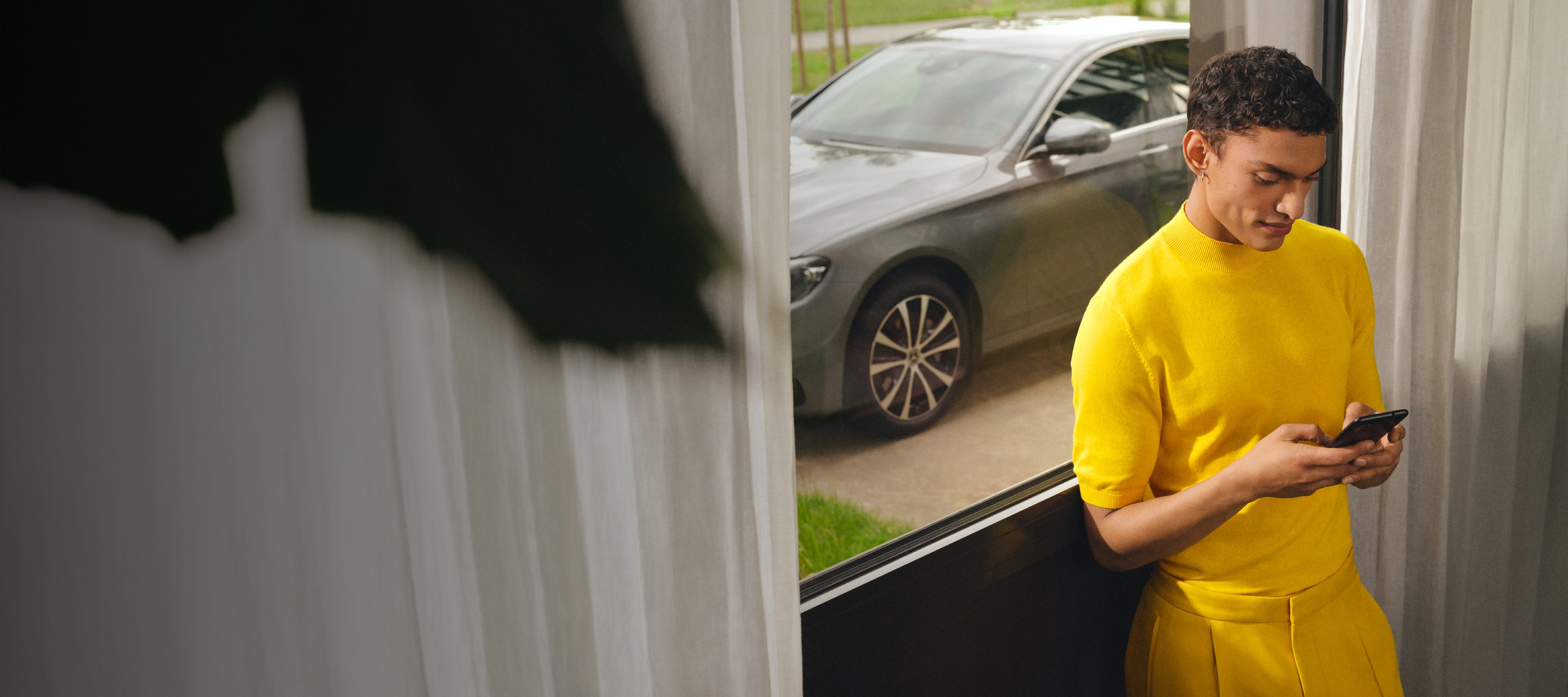 A man is connected to his Mercedes-Benz via Digital Extras on his smartphone. A man is connected to his Mercedes-Benz via Digital Extras on his smartphone.