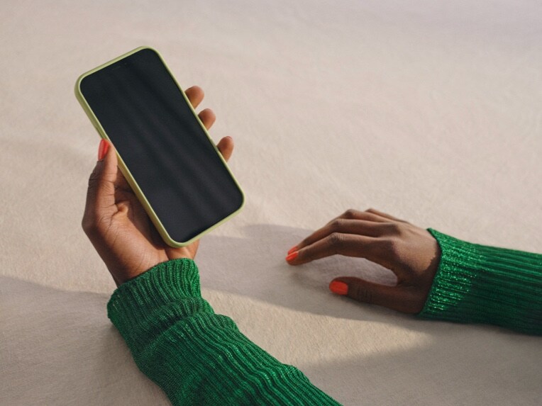 Someone is holding a smartphone that is connected to a Mercedes-Benz via Digital Extras.