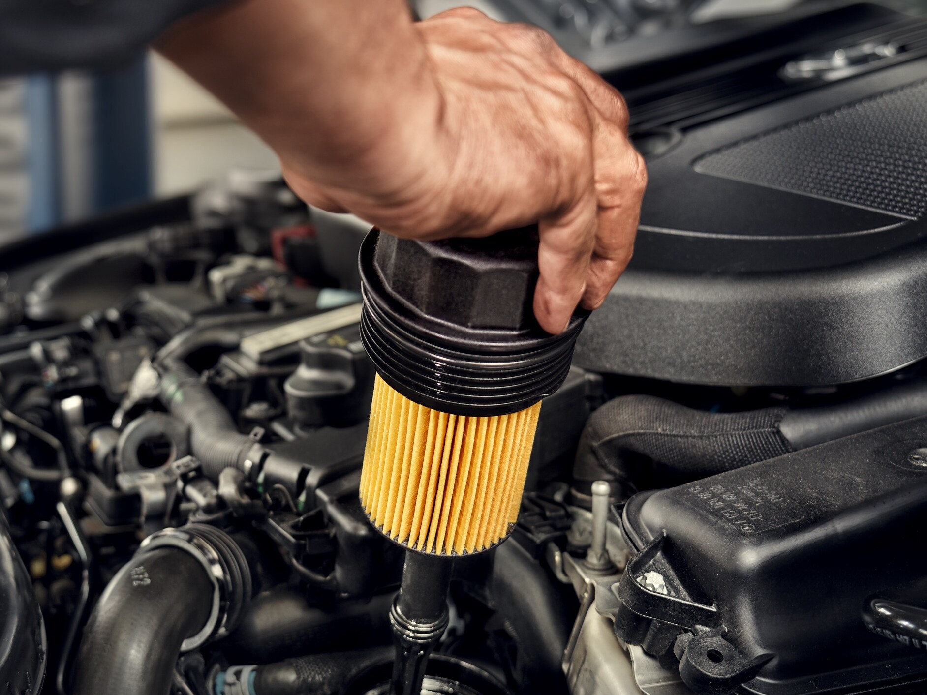 A technician installing the oil filter to the Mercedes-Benz vehicle.