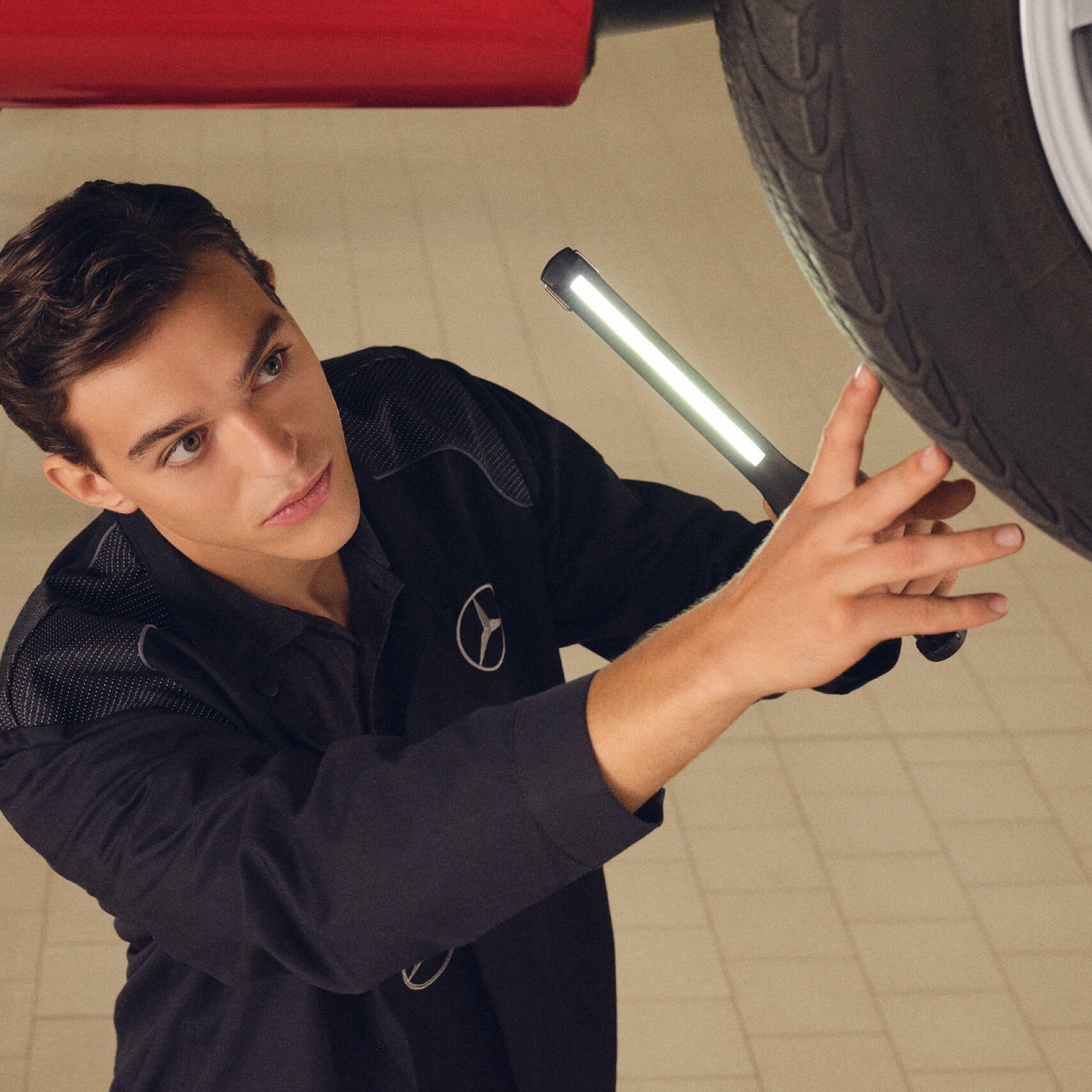 A Mercedes-Benz technician checks the underside of a vehicle.