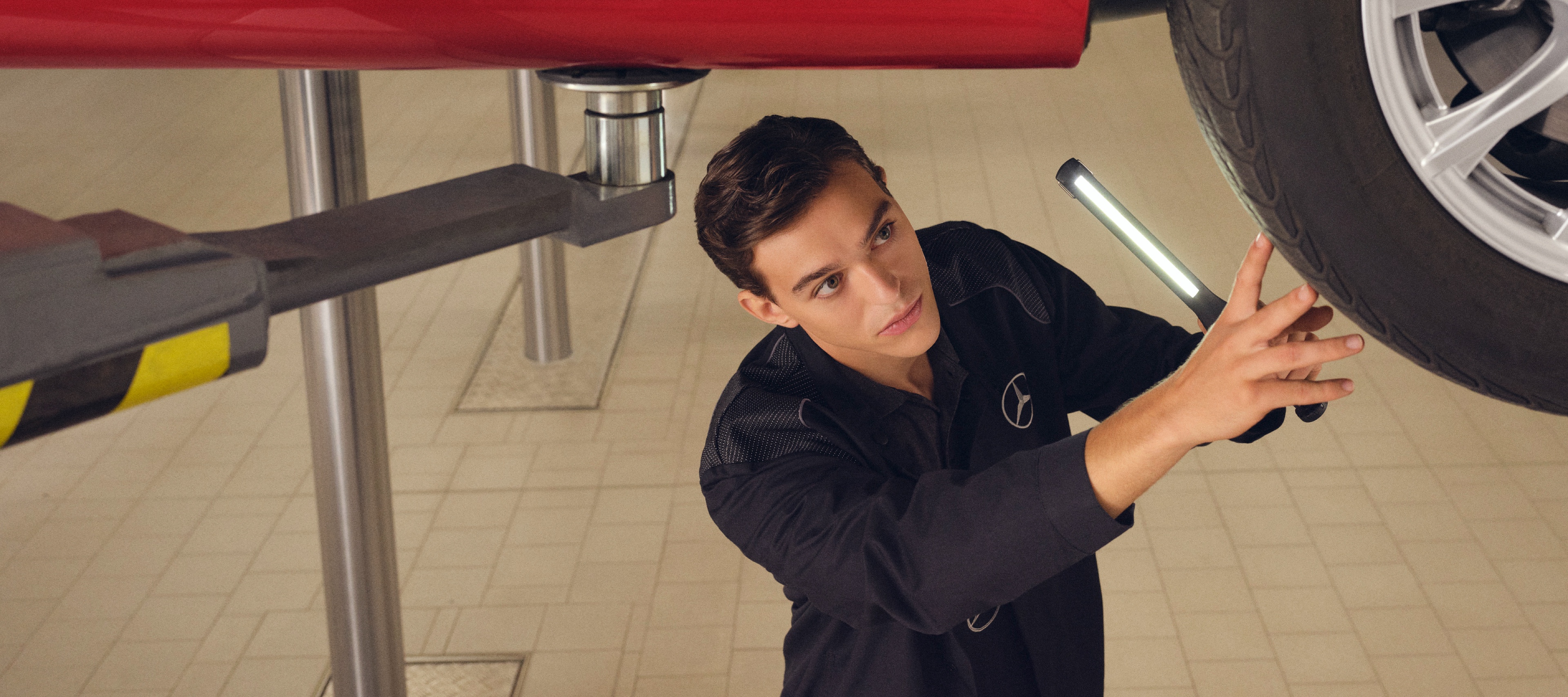 Mercedes-Benz replacement parts. A Mercedes-Benz technician checks the underside of a vehicle.