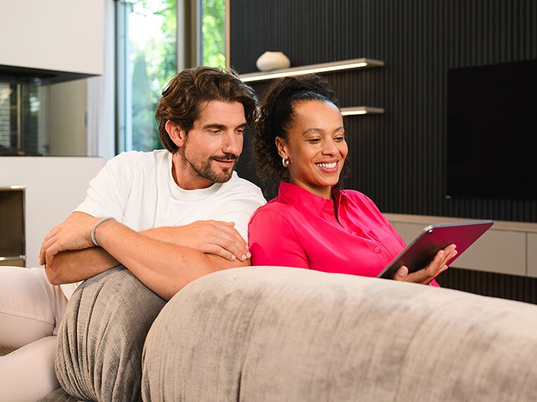 A man and woman on the couch looking at a tablet