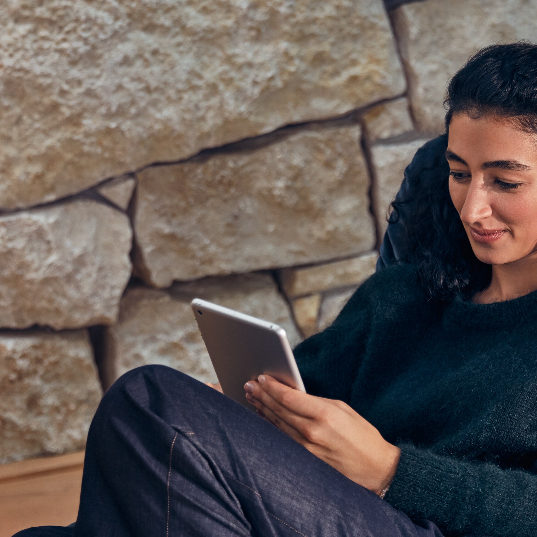 A person seated in comfort, interacting with tablet device.