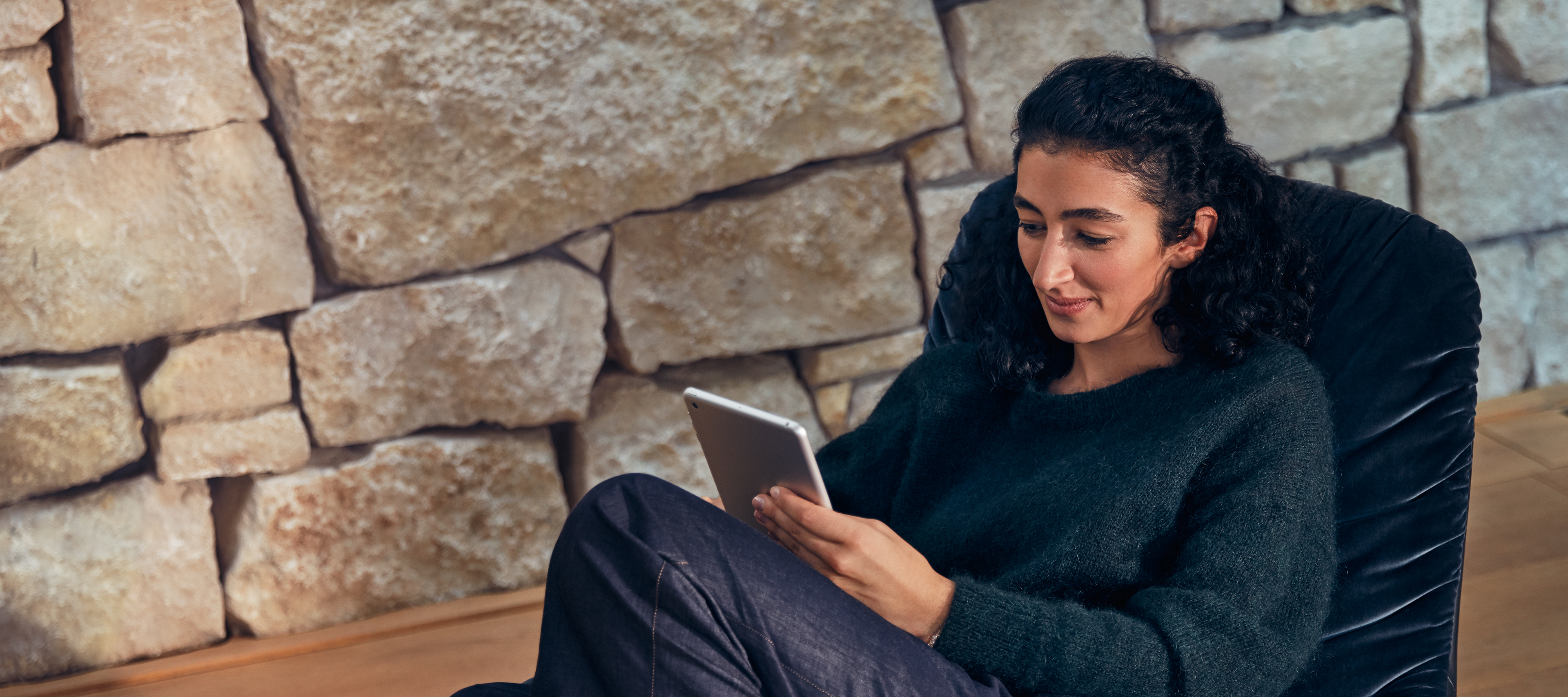 How to buy online. A person seated in comfort, interacting with tablet device.