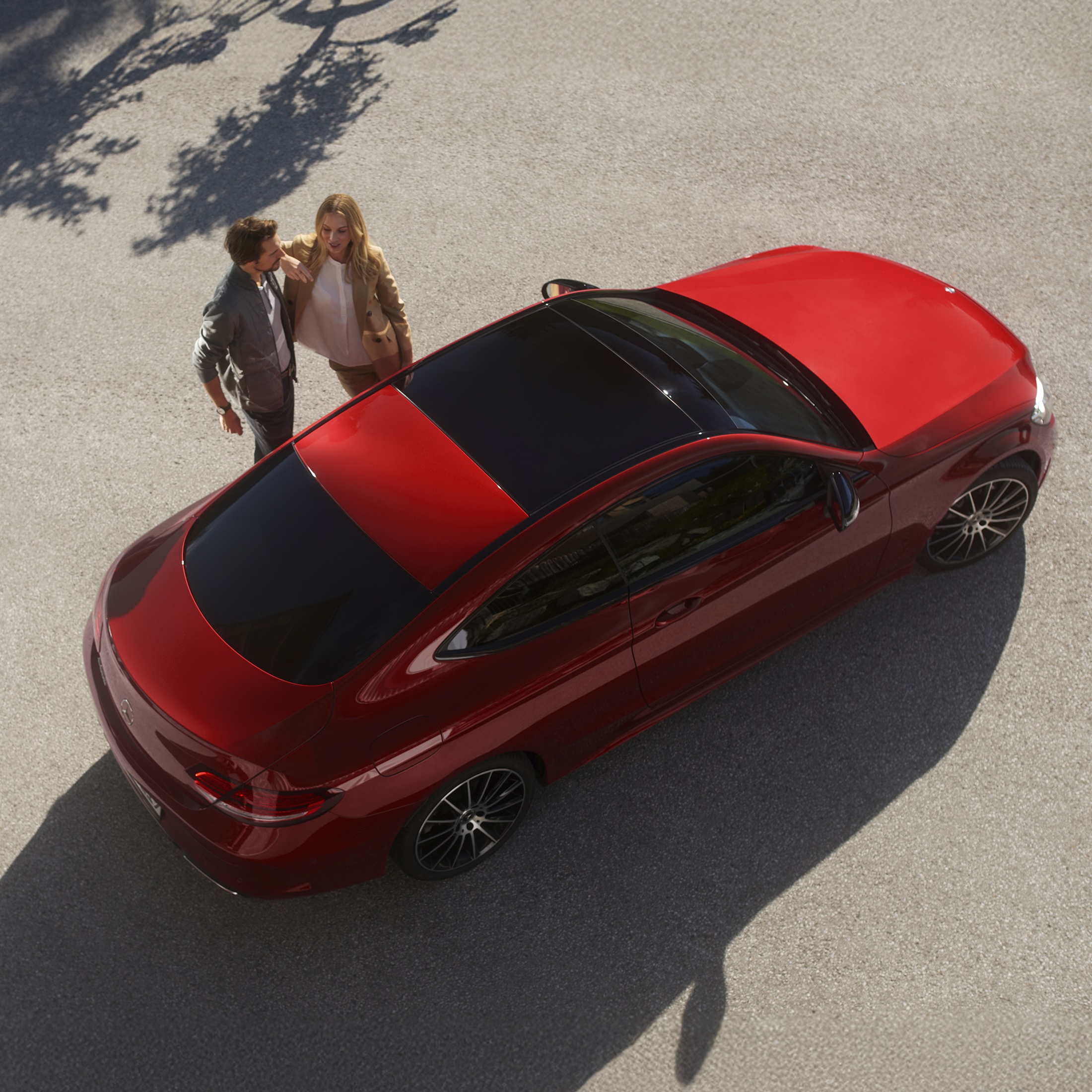 Complimentary vehicle check A man and woman standing next to a red Mercedes-Benz