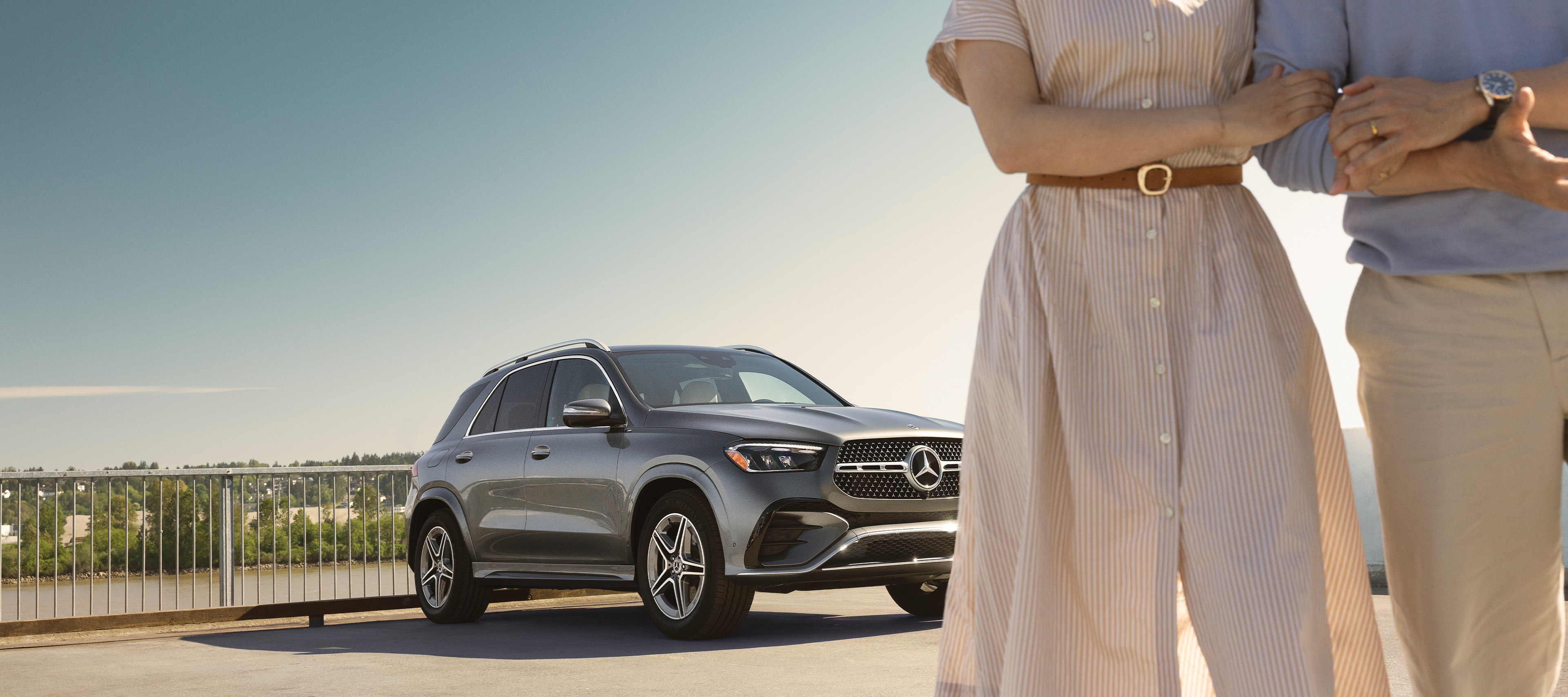 Own the moment | Mercedes-Benz Mercedes-Benz SUV parked outdoors with two people partially visible in the foreground